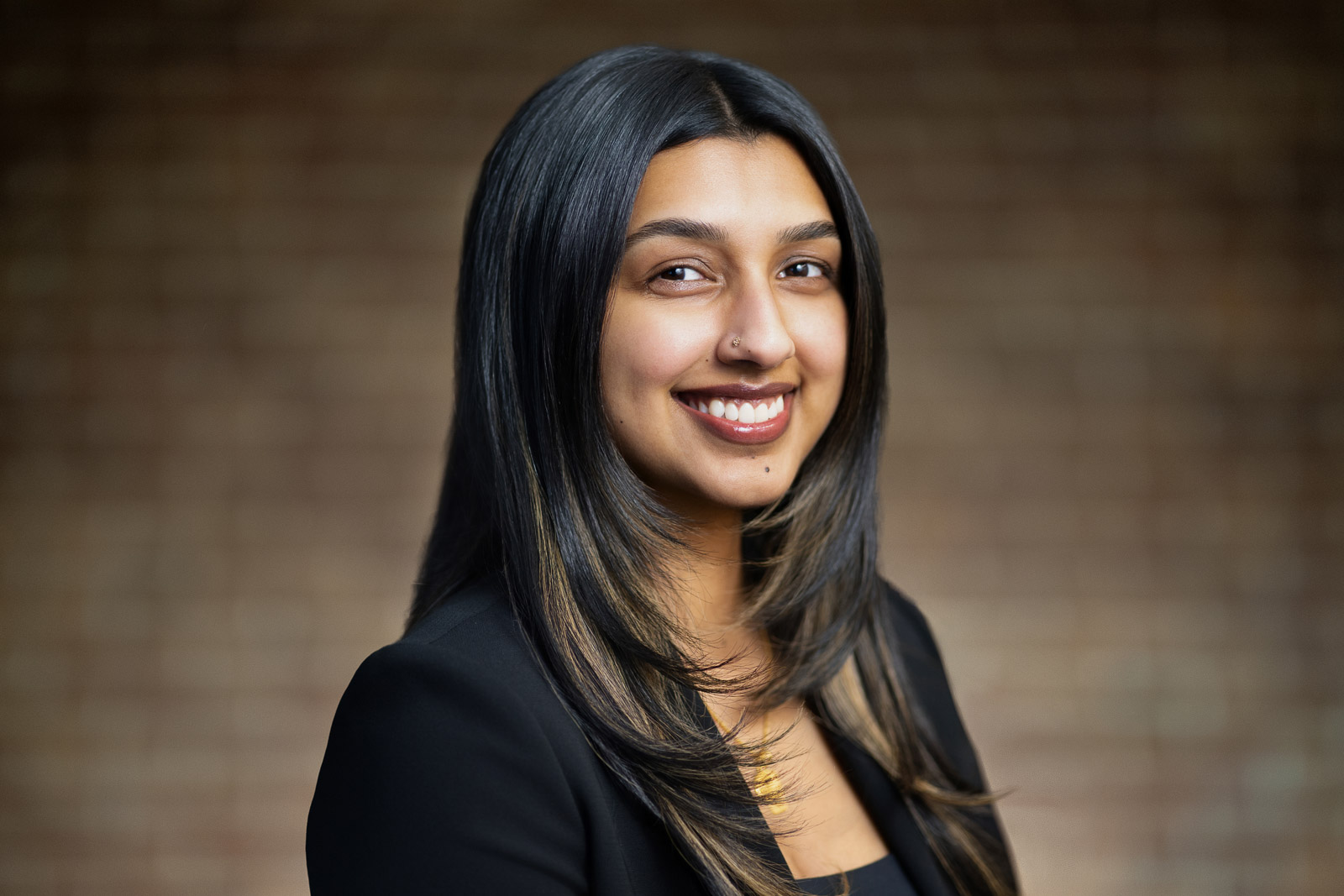 Young woman in black blazer with confident bright smile during LinkedIn headshot session in NJ studio