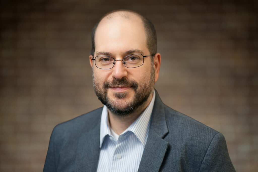Male professional in glasses and gray blazer with relaxed natural expression during NJ headshot session