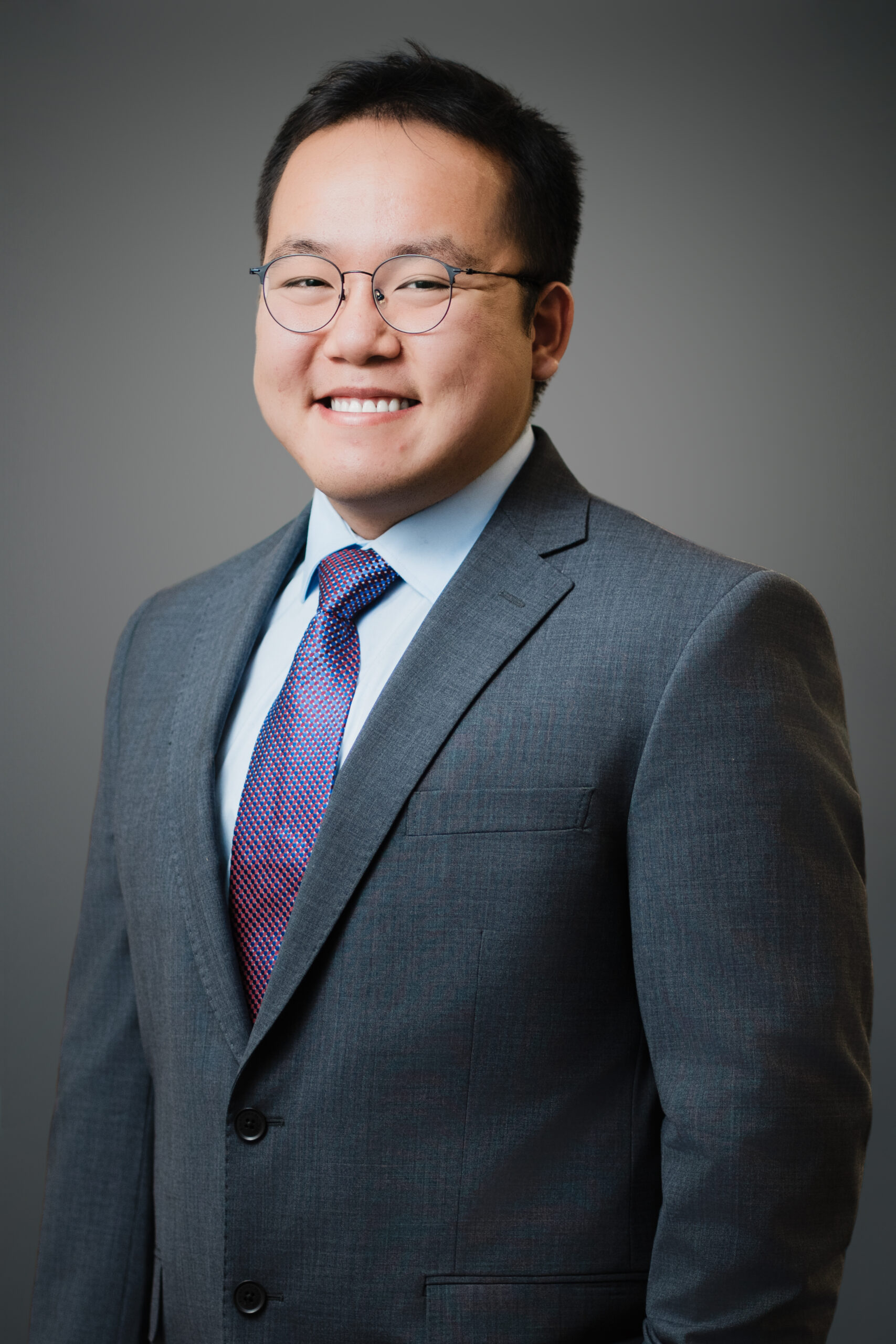 William in a gray suit smiling in a professional LinkedIn headshot by Alex Kaplan photographer