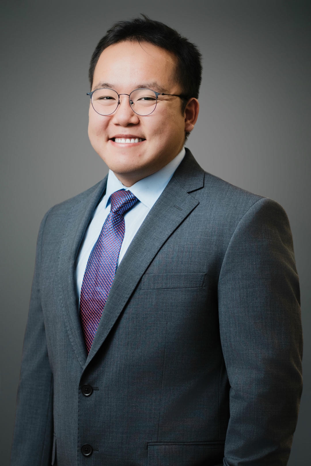 William in a gray suit smiling in a professional LinkedIn headshot by Alex Kaplan photographer