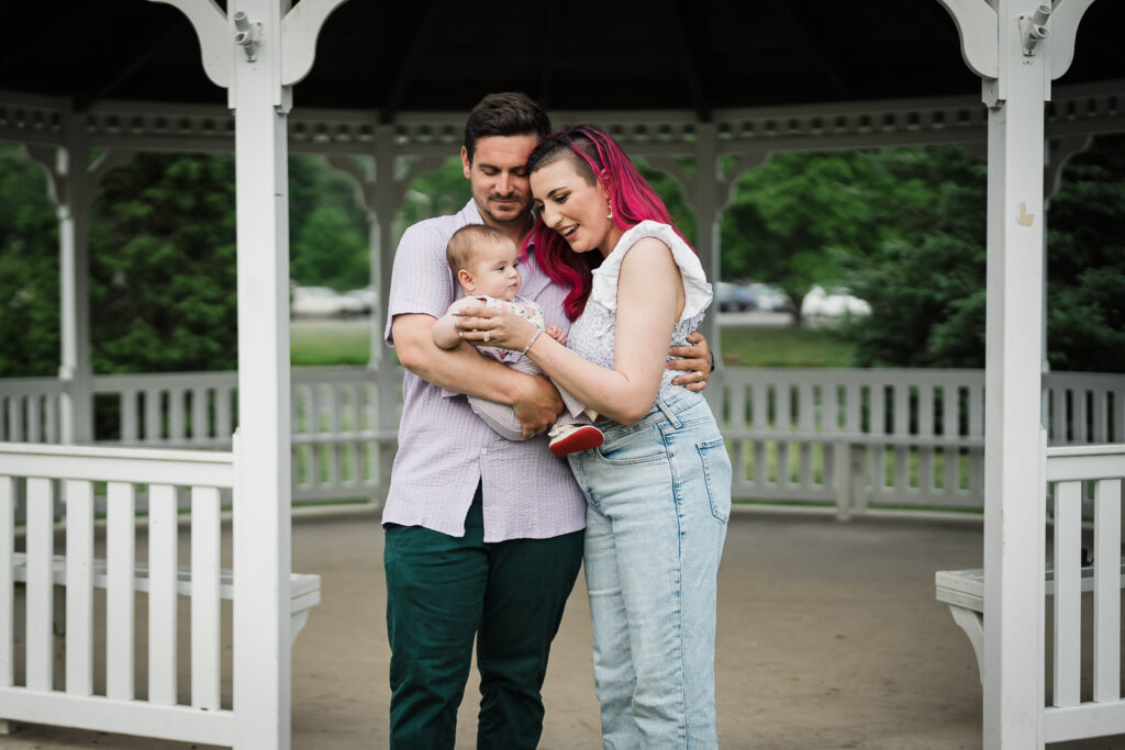 Parents holding their baby together inside the gazebo at Crane Park in Monroe NY