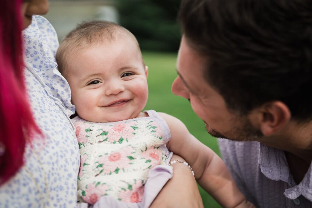 Baby smiling with parents during family portraits in Monroe NY