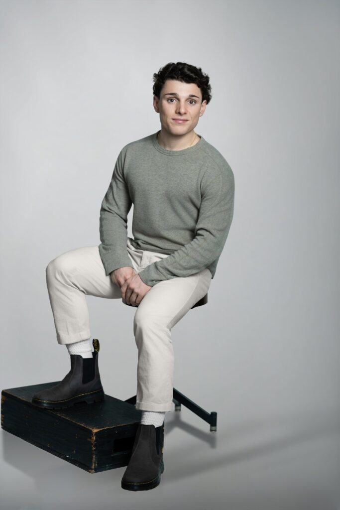 Young male model seated during a relaxed modeling portrait session in New Milford