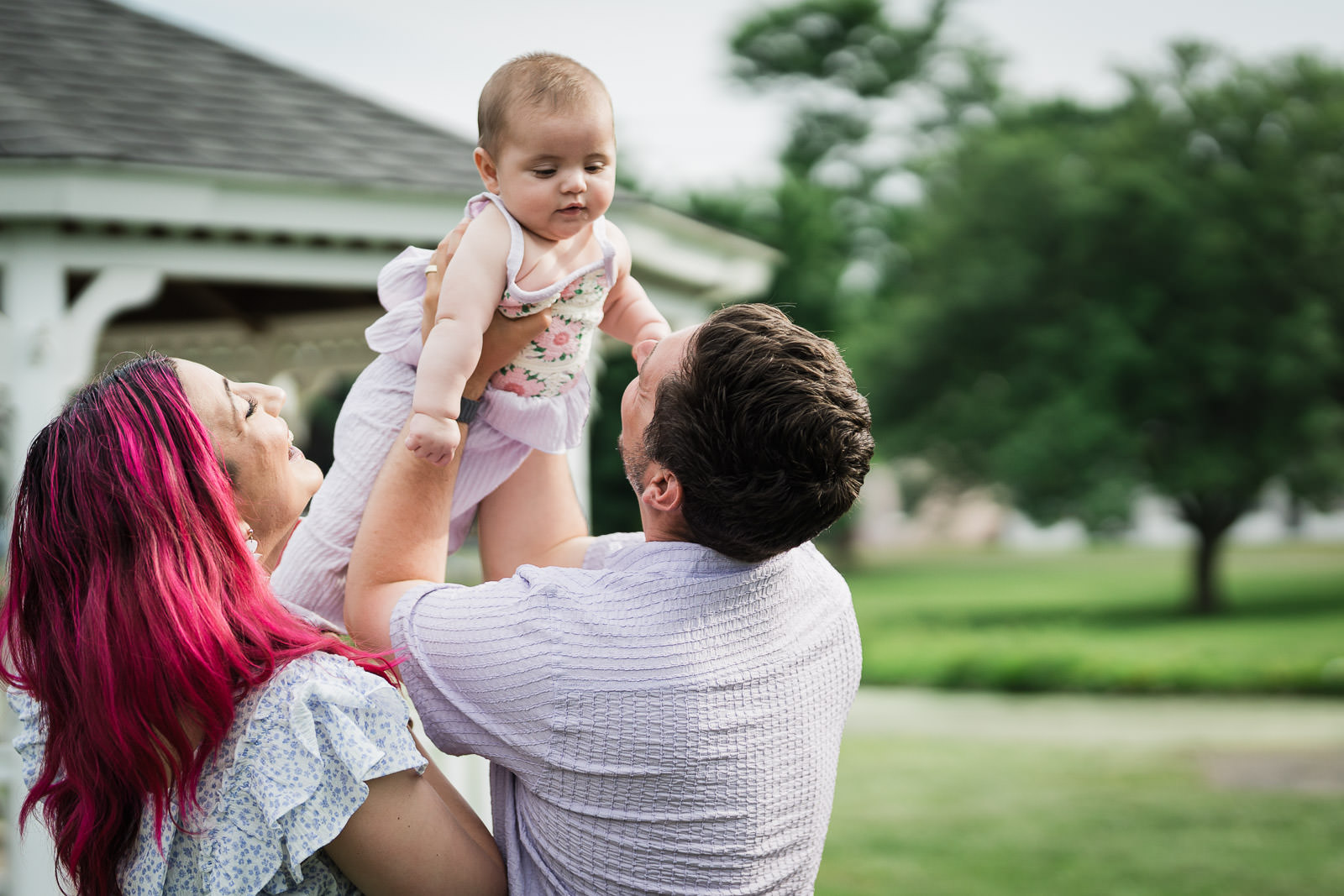 Parents lifting their baby in the air during an outdoor family session in New Jersey