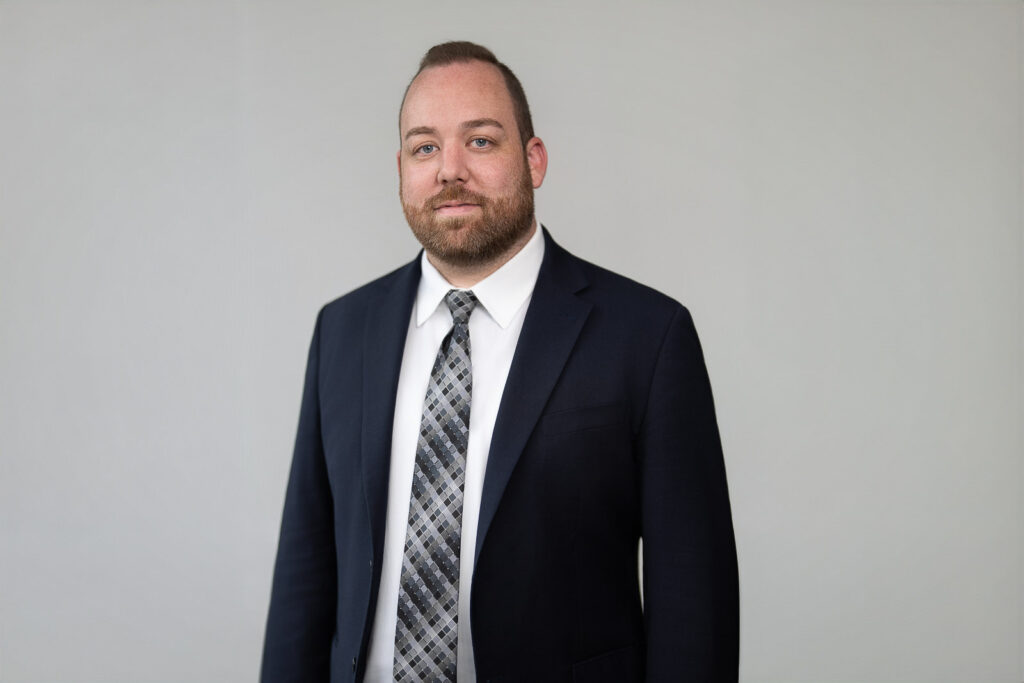 Professional headshot of William Gosling wearing a navy suit and patterned tie against a neutral background