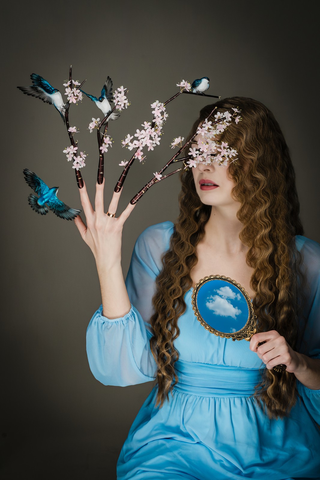 Model holding a sky mirror with cherry blossom nail art in a Northern New Jersey studio