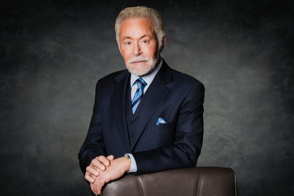 Seated attorney in navy suit posing for executive headshot in New Jersey office.