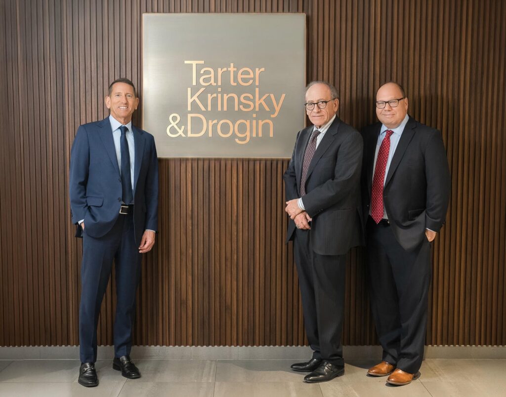 Three law firm founders standing in front of firm logo wall during 25th anniversary professional photography session