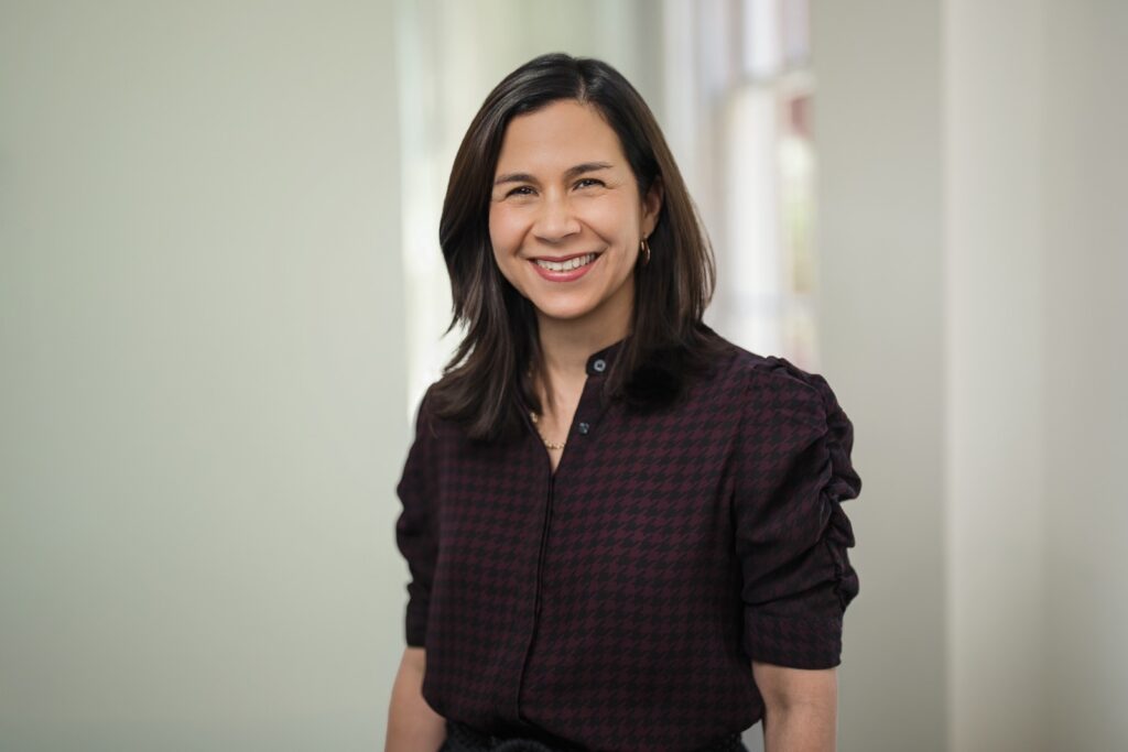 Approachable executive smiling warmly during a business headshot session in a sunlit office setting
