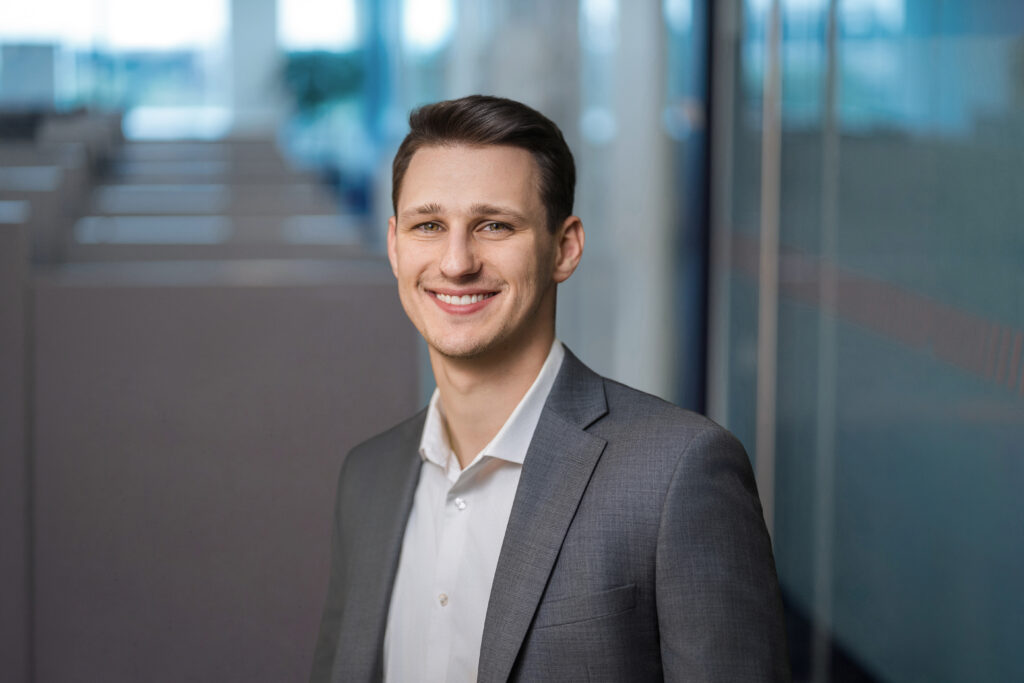 Younger employee photographed beside glass partitions at a Long Island office
