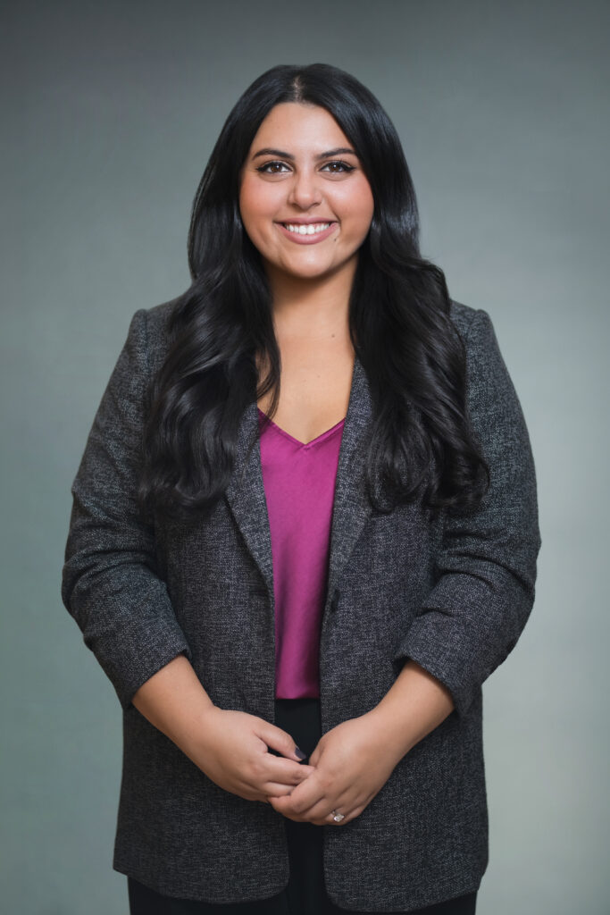 Woman in a charcoal blazer photographed with soft professional headshot lighting