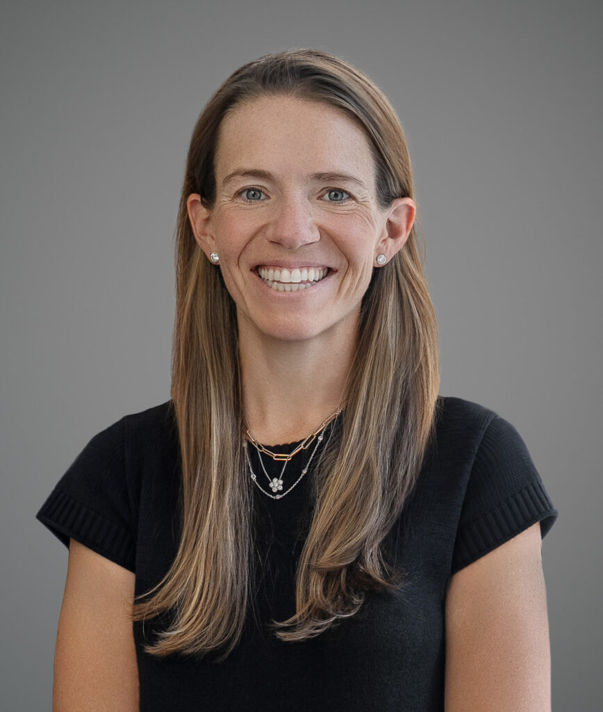 Charlotte Schwartz smiling in a professional headshot with a neutral gray background