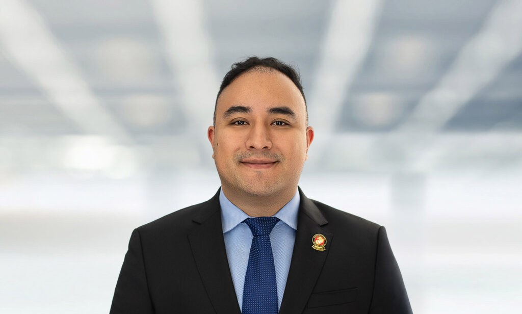 Attorney in suit and blue tie photographed for consistent law firm headshots against blurred office background