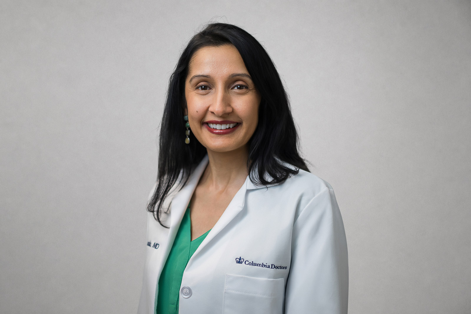 Smiling physician in a white coat photographed for medical team headshots in Yonkers NY
