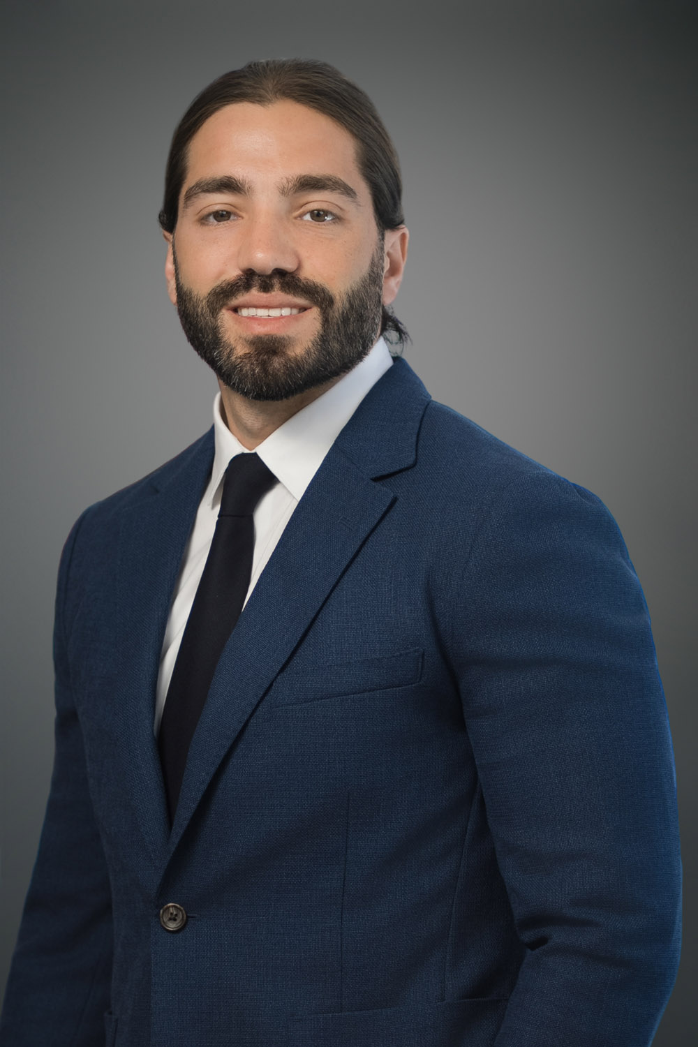 Business professional with groomed beard posing for an executive headshot in an office setting