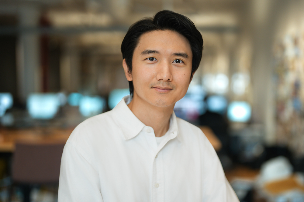 Employee in a white shirt photographed against an open office background in New York City