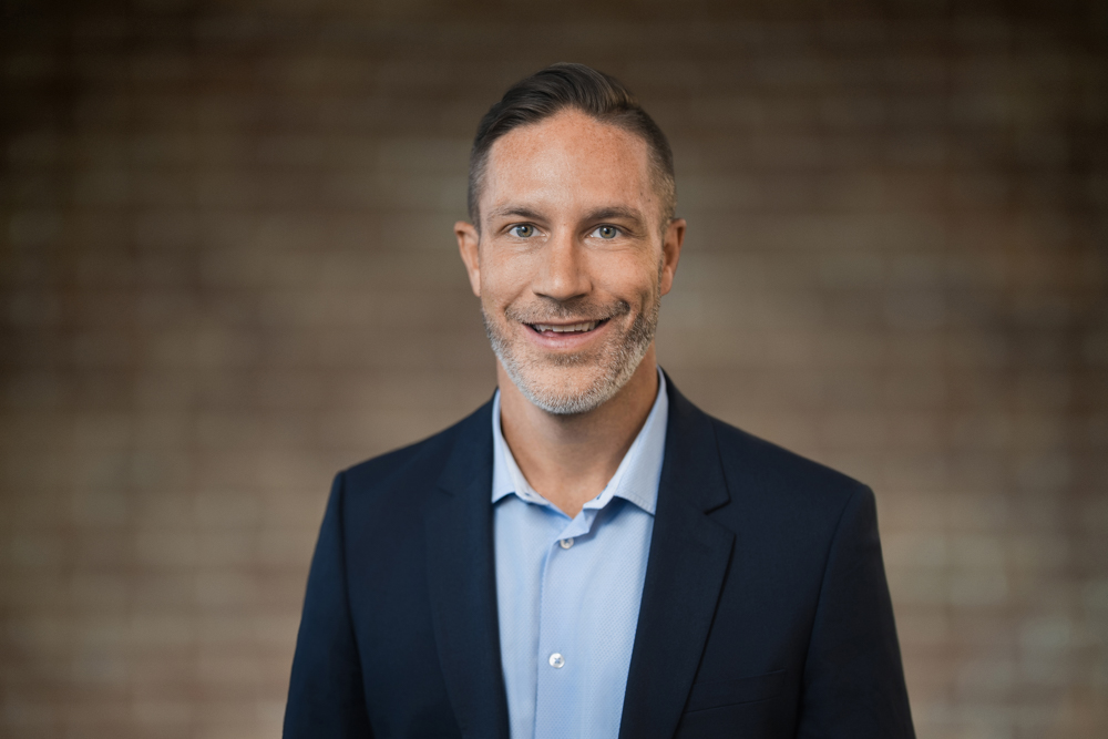 Professional headshot with a softly blurred background photographed by Alex Kaplan
