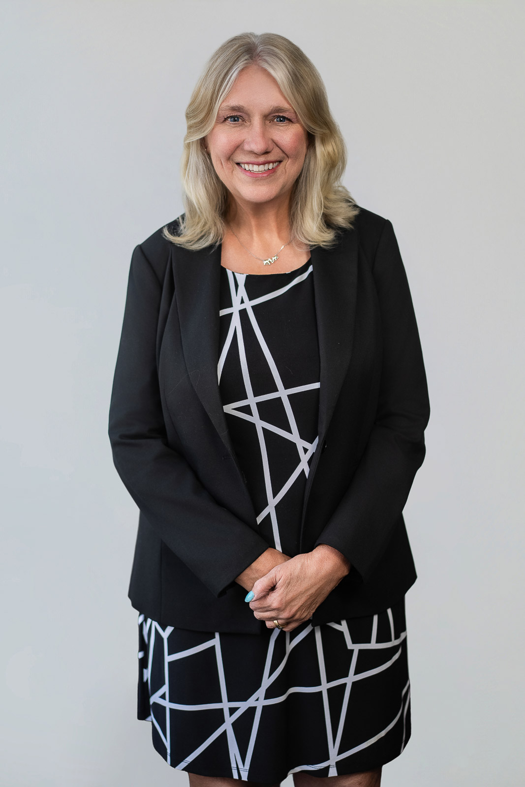 Professional headshot showing a polished business style with a blazer and approachable expression