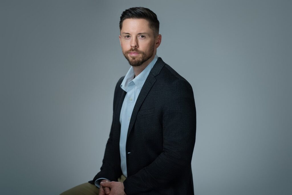 ale professional seated with hands relaxed during a headshot session in a New Jersey studio