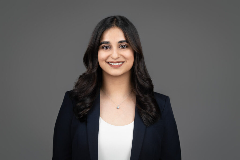 Smiling professional woman in a navy blazer against a gray studio background
