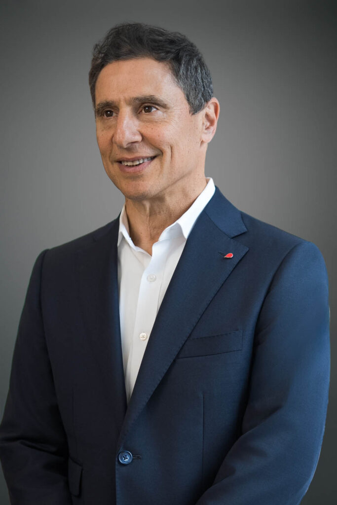 Executive with a subtle smile photographed against a studio backdrop for a professional headshot
