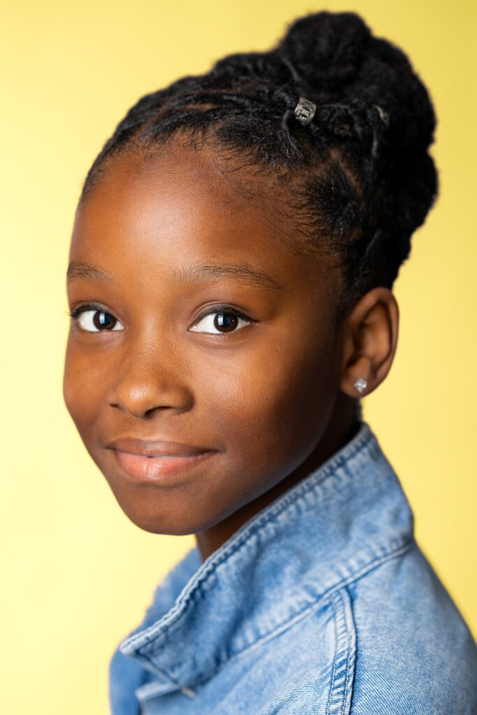Child actor in NJ with a calm composed expression on a yellow studio backdrop