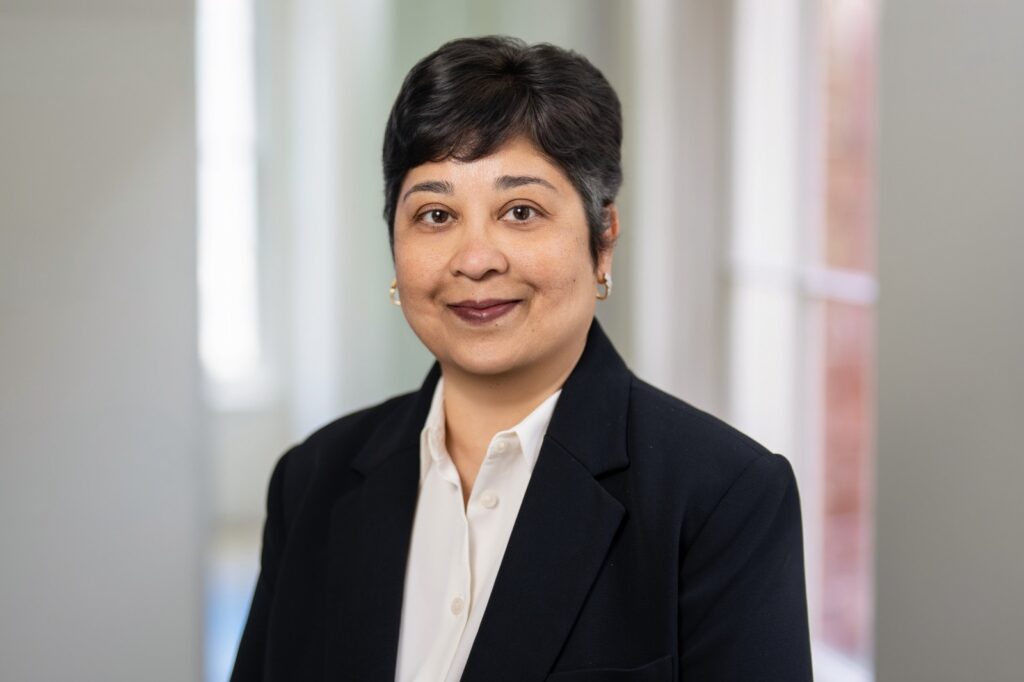 Team member in navy blazer and white blouse photographed for a corporate headshot in an office