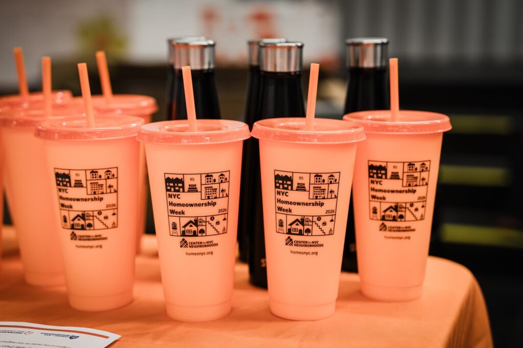 Branded orange tumblers displayed on a table at the Bronx Homeowner Help Clinic event