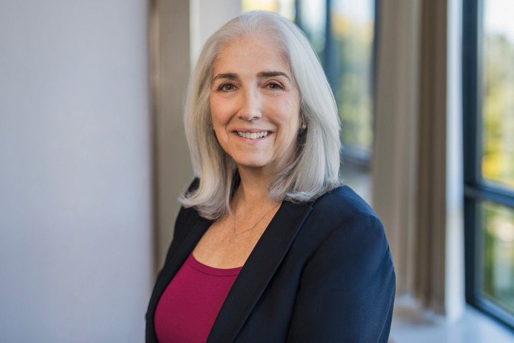 Financial advisor in navy blazer and magenta top smiling during an office headshot session