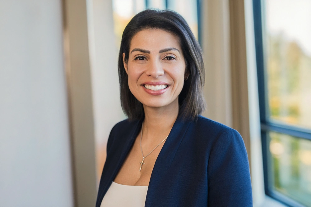 Smiling financial advisor in a navy blazer photographed indoors beside office windows