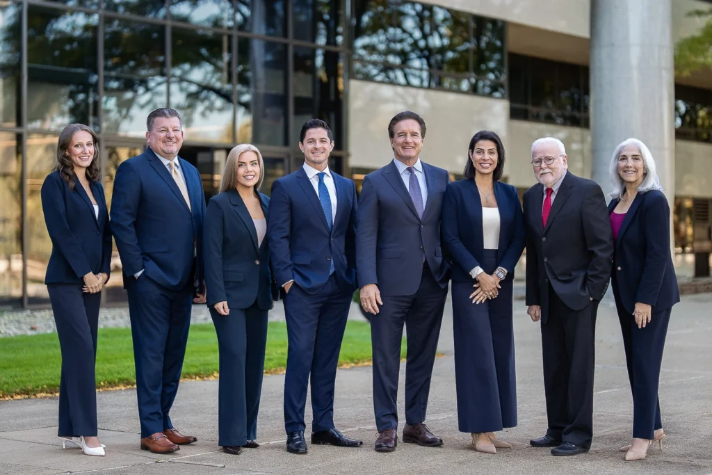 Eight team members in navy business attire posing outside an office building