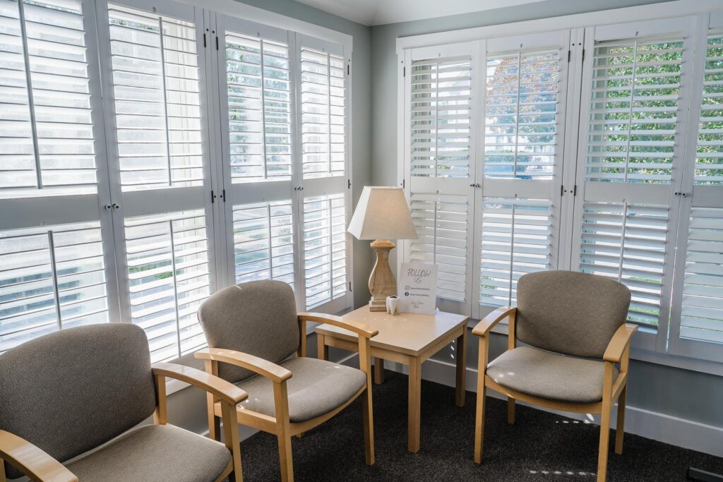 Sunlit waiting area with armchairs and plantation shutters photographed in a Manasquan dental practice
