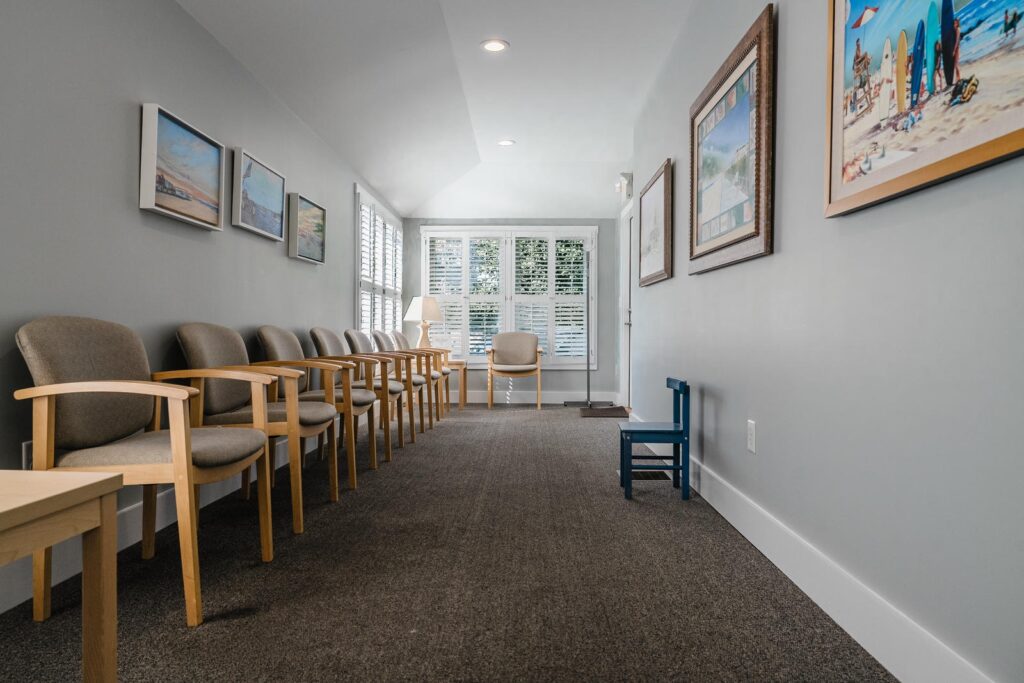 Waiting room with wooden chairs and coastal artwork in a Manasquan, New Jersey dental office