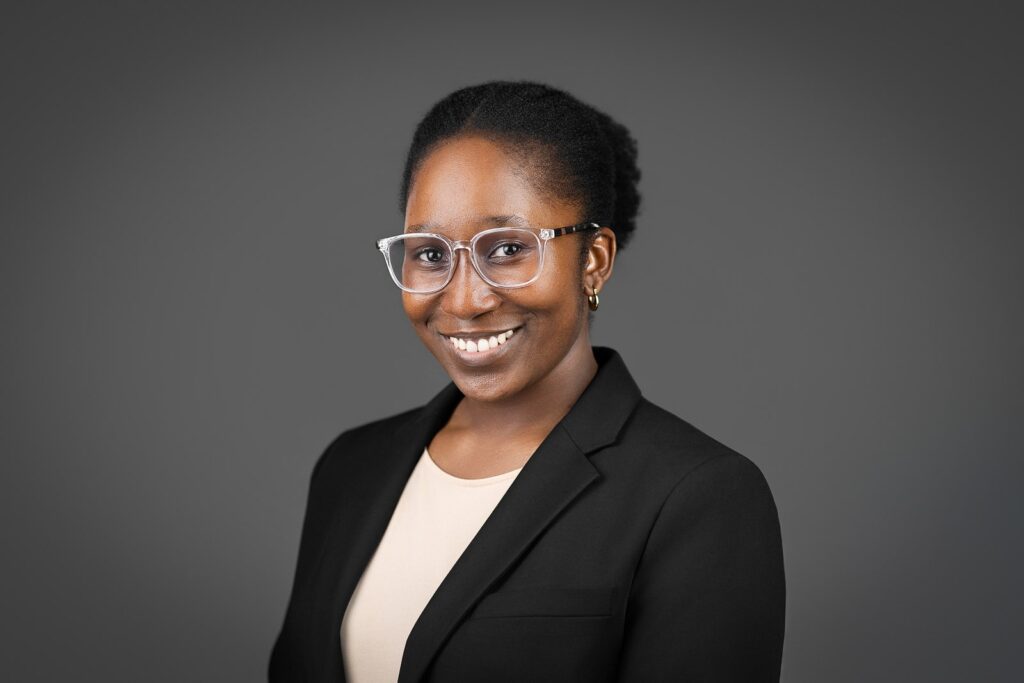 Smiling woman in clear glasses and black blazer during professional headshot session in New Jersey studio