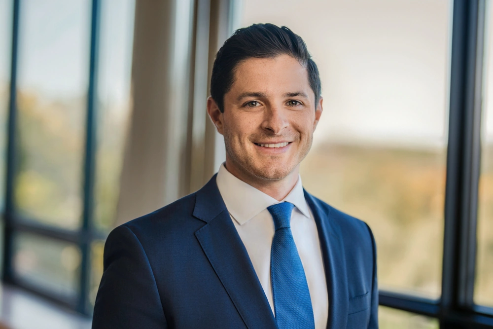 Financial advisor in a blue tie photographed beside office windows