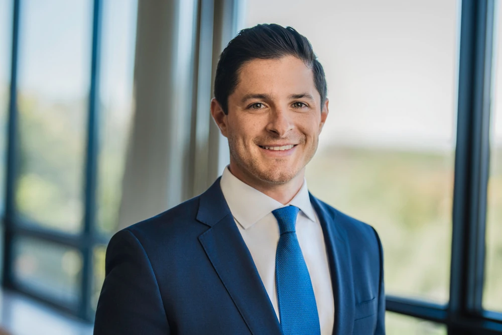 Financial advisor in a blue tie photographed beside office windows