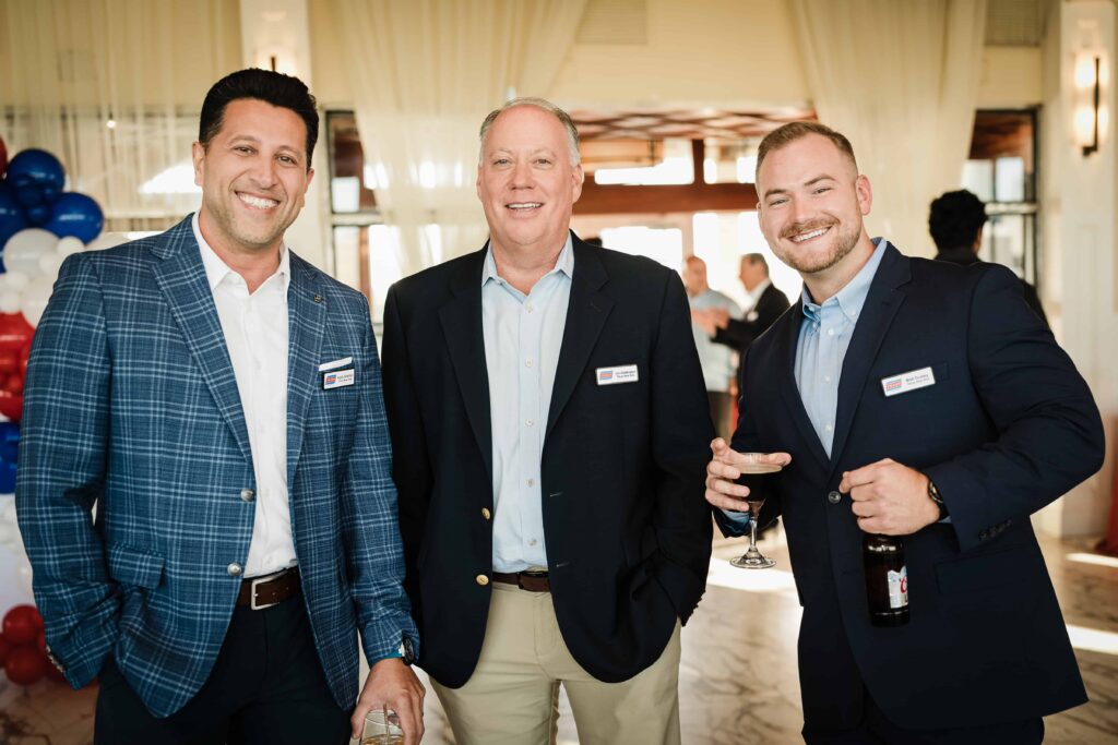 Three smiling guests wearing Tilcon New York name badges at the corporate event at Liberty House