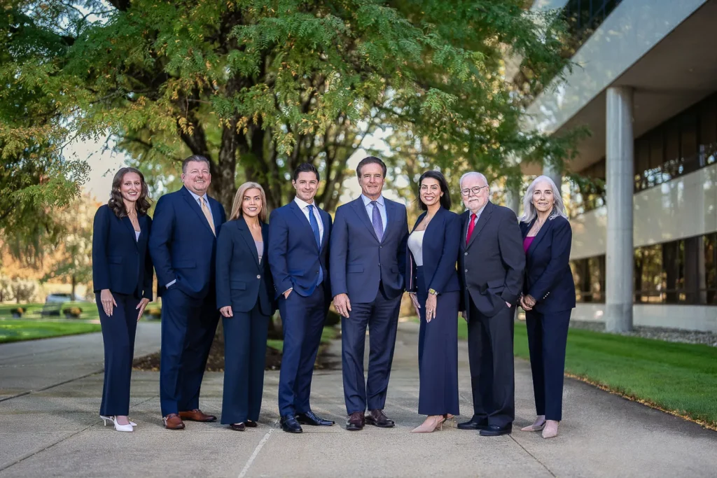 Wealth management team of eight in navy attire standing together on a tree-lined office walkway